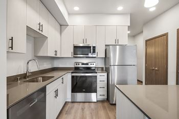 an empty kitchen with white cabinets and stainless steel appliances